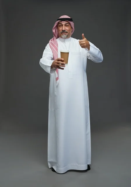 رجل  عربي سعودي خليجي مسن يرتدي الزي الثوب الابيض والشماغ ويحمل فنجان قهوة,  ايماءات واشارات مختلفه , كامل الجسم, خلفيه رماديه