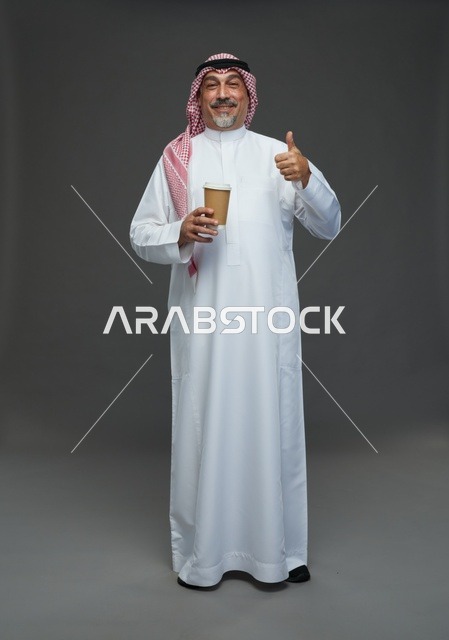 رجل  عربي سعودي خليجي مسن يرتدي الزي الثوب الابيض والشماغ ويحمل فنجان قهوة,  ايماءات واشارات مختلفه , كامل الجسم, خلفيه رماديه