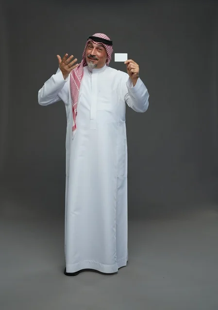 رجل  عربي سعودي خليجي مسن يرتدي الزي الثوب الابيض والشماغ ويمسك بطاقه بيضاء فارغه,  ايماءات واشارات مختلفه , كامل الجسم, خلفيه رماديه