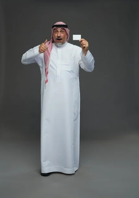 رجل  عربي سعودي خليجي مسن يرتدي الزي الثوب الابيض والشماغ ويمسك بطاقه بيضاء فارغه,  ايماءات واشارات مختلفه , كامل الجسم, خلفيه رماديه