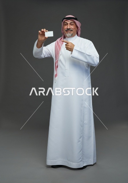 An elderly Arab Saudi Gulf man wearing a white thobe and a shemagh, holding a blank white card, with various gestures and signs, full body, gray background.