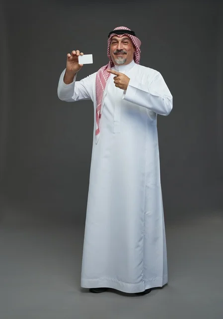 An elderly Arab Saudi Gulf man wearing a white thobe and a shemagh, holding a blank white card, with various gestures and signs, full body, gray background.
