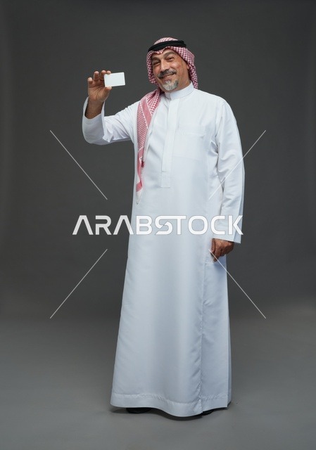 رجل  عربي سعودي خليجي مسن يرتدي الزي الثوب الابيض والشماغ ويمسك بطاقه بيضاء فارغه,  ايماءات واشارات مختلفه , كامل الجسم, خلفيه رماديه