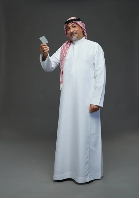 رجل  عربي سعودي خليجي مسن يرتدي الزي الثوب الابيض والشماغ ويمسك بطاقه بيضاء فارغه,  ايماءات واشارات مختلفه , كامل الجسم, خلفيه رماديه