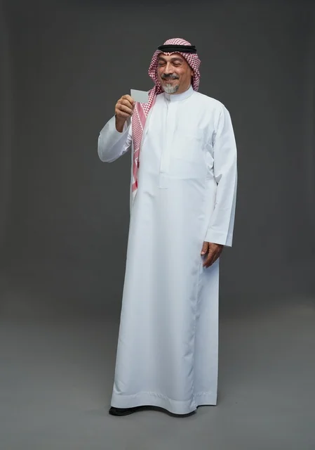 An elderly Arab Saudi Gulf man wearing a white thobe and a shemagh, holding a blank white card, with various gestures and signs, full body, gray background.