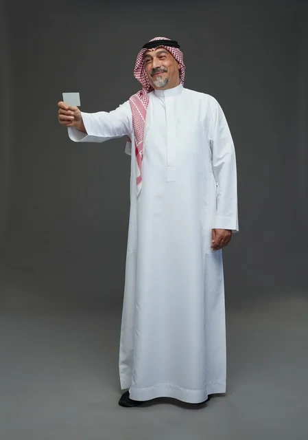 رجل  عربي سعودي خليجي مسن يرتدي الزي الثوب الابيض والشماغ ويمسك بطاقه بيضاء فارغه,  ايماءات واشارات مختلفه , كامل الجسم, خلفيه رماديه