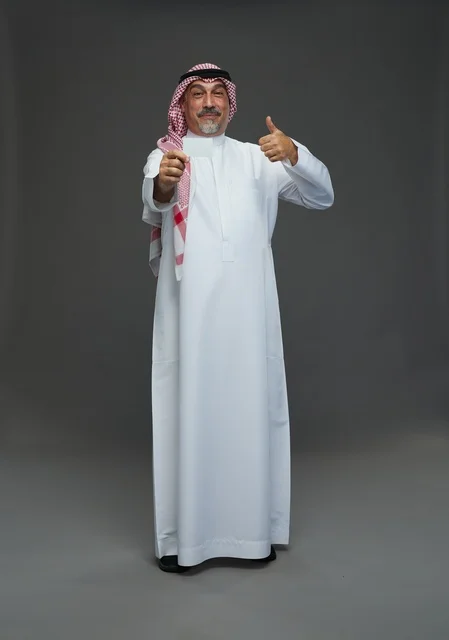 رجل  عربي سعودي خليجي مسن يرتدي الزي الثوب الابيض والشماغ ويمسك بطاقه بيضاء فارغه,  ايماءات واشارات مختلفه , كامل الجسم, خلفيه رماديه