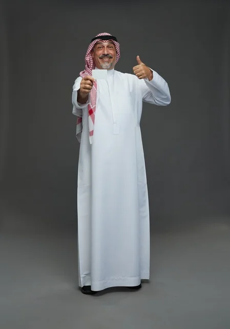 رجل  عربي سعودي خليجي مسن يرتدي الزي الثوب الابيض والشماغ ويمسك بطاقه بيضاء فارغه,  ايماءات واشارات مختلفه , كامل الجسم, خلفيه رماديه