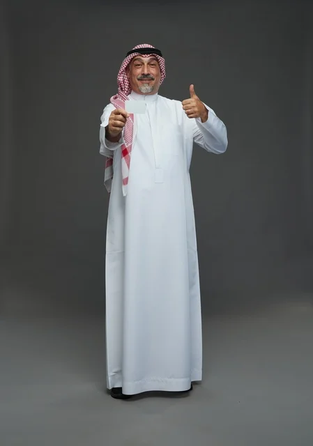An elderly Arab Saudi Gulf man wearing a white thobe and a shemagh, holding a blank white card, with various gestures and signs, full body, gray background.