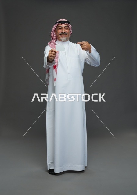 An elderly Arab Saudi Gulf man wearing a white thobe and a shemagh, holding a blank white card, with various gestures and signs, full body, gray background.