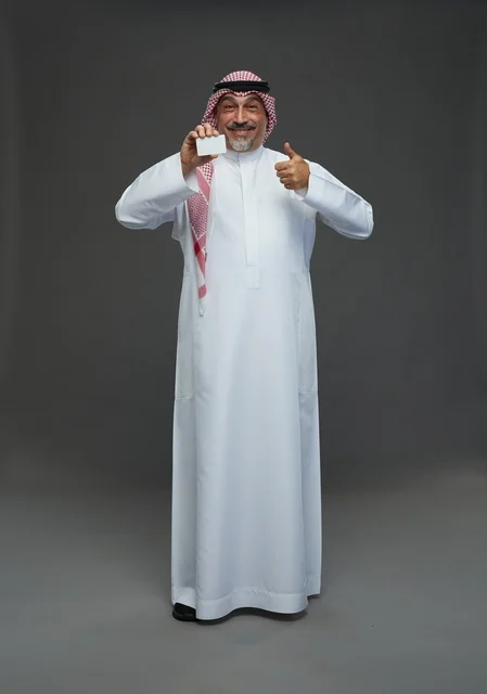 رجل  عربي سعودي خليجي مسن يرتدي الزي الثوب الابيض والشماغ ويمسك بطاقه بيضاء فارغه,  ايماءات واشارات مختلفه , كامل الجسم, خلفيه رماديه