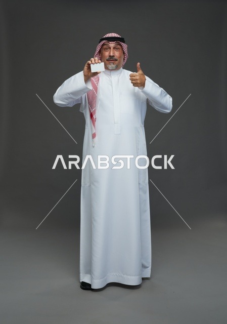 رجل  عربي سعودي خليجي مسن يرتدي الزي الثوب الابيض والشماغ ويمسك بطاقه بيضاء فارغه,  ايماءات واشارات مختلفه , كامل الجسم, خلفيه رماديه