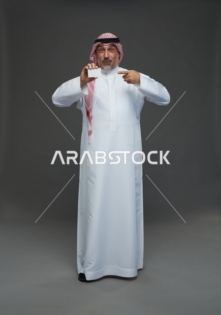An elderly Arab Saudi Gulf man wearing a white thobe and a shemagh, holding a blank white card, with various gestures and signs, full body, gray background.