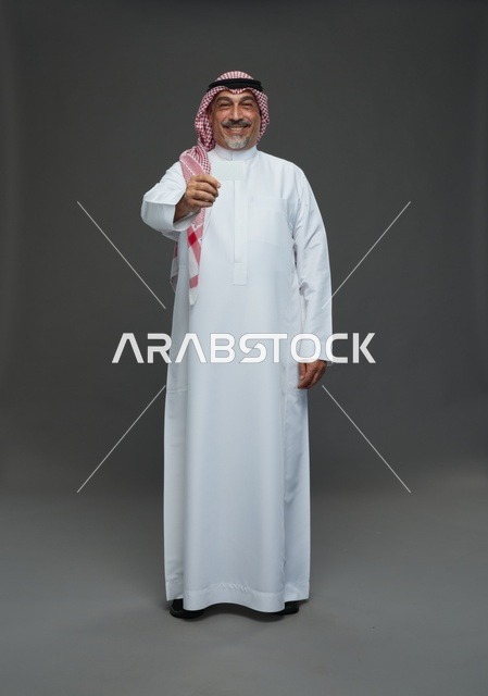 رجل  عربي سعودي خليجي مسن يرتدي الزي الثوب الابيض والشماغ ويمسك بطاقه بيضاء فارغه,  ايماءات واشارات مختلفه , كامل الجسم, خلفيه رماديه