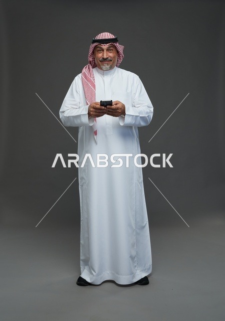 An elderly Arab Saudi Gulf man wearing a white thobe and a shemagh, holding a mobile phone, with various gestures and signals, full body, gray background.