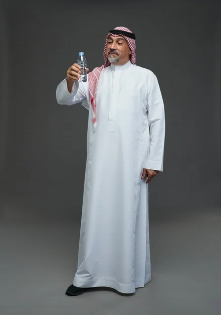 An elderly Arab Saudi Gulf man wearing a white thobe and a shemagh, holding a water bottle, with various gestures and signs, full body, gray background.
