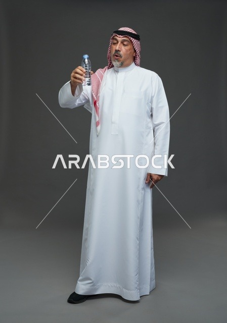 رجل  عربي سعودي خليجي مسن يرتدي الزي الثوب الابيض والشماغ ويحمل قارورة ماء,  ايماءات واشارات مختلفه , كامل الجسم, خلفيه رماديه