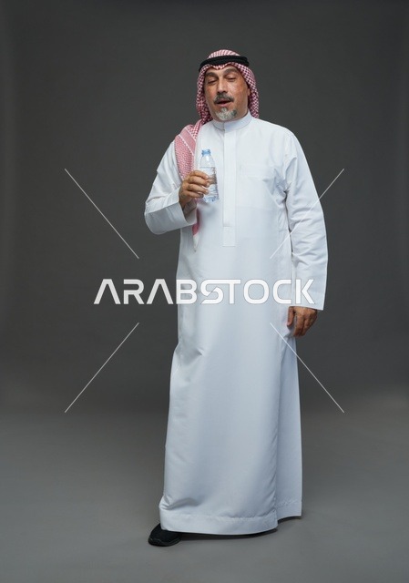 رجل  عربي سعودي خليجي مسن يرتدي الزي الثوب الابيض والشماغ ويحمل قارورة ماء,  ايماءات واشارات مختلفه , كامل الجسم, خلفيه رماديه