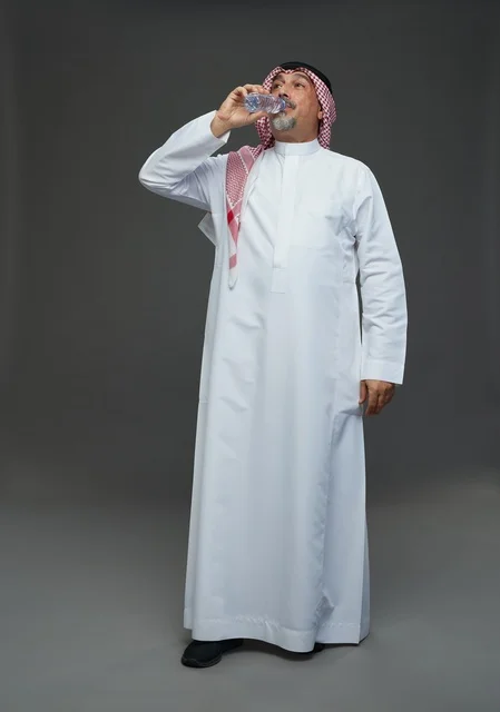 An elderly Arab Saudi Gulf man wearing a white thobe and a shemagh, holding a water bottle, with various gestures and signs, full body, gray background.