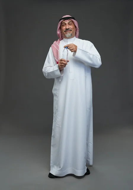 An elderly Arab Saudi Gulf man wearing a white thobe and a shemagh, holding a water bottle, with various gestures and signs, full body, gray background.