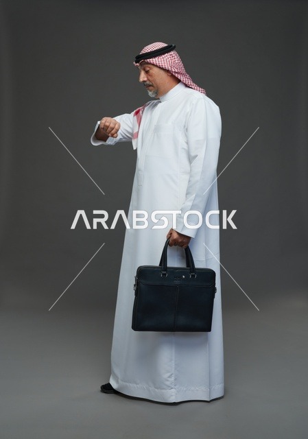 رجل اعمال عربي سعودي خليجي  يرتدي الزي الثوب الابيض والشماغ ويحمل حقيبة اللابتوب,  ايماءات واشارات مختلفه , كامل الجسم, خلفيه رماديه