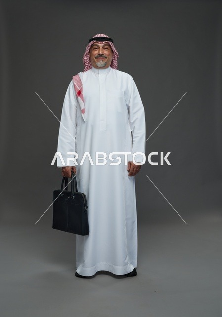 رجل اعمال عربي سعودي خليجي  يرتدي الزي الثوب الابيض والشماغ ويحمل حقيبة اللابتوب,  ايماءات واشارات مختلفه , كامل الجسم, خلفيه رماديه