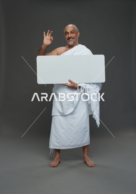 A portrait of a Saudi pilgrim in Ihram clothing holding a blank white square board while performing the rituals, with various gestures and signs, full body, gray background.