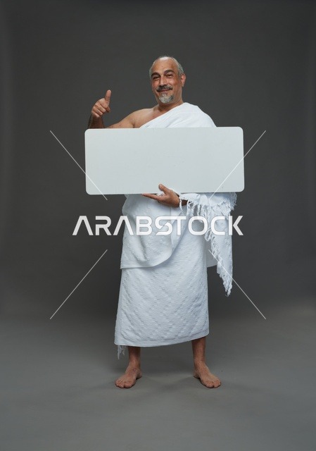 A portrait of a Saudi pilgrim in Ihram clothing holding a blank white square board while performing the rituals, with various gestures and signs, full body, gray background.