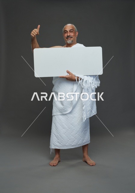 A portrait of a Saudi pilgrim in Ihram clothing holding a blank white square board while performing the rituals, with various gestures and signs, full body, gray background.