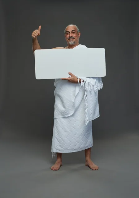 A portrait of a Saudi pilgrim in Ihram clothing holding a blank white square board while performing the rituals, with various gestures and signs, full body, gray background.