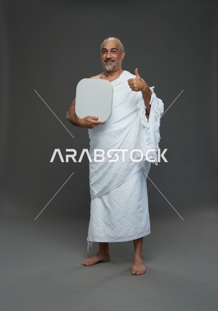 A portrait of a Saudi pilgrim in Ihram clothing holding a blank white square board while performing the rituals, with various gestures and signs, full body, gray background.