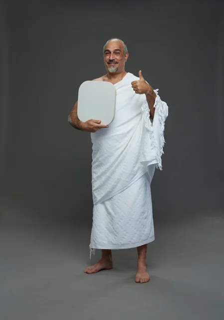 بورتريه لحاج سعودي بملابس الإحرام يحمل لوح مربع ابيض فارغ أثناء أداء المناسك, ايماءات واشارات مختلفه, كامل الجسم, خلفيه رماديه
