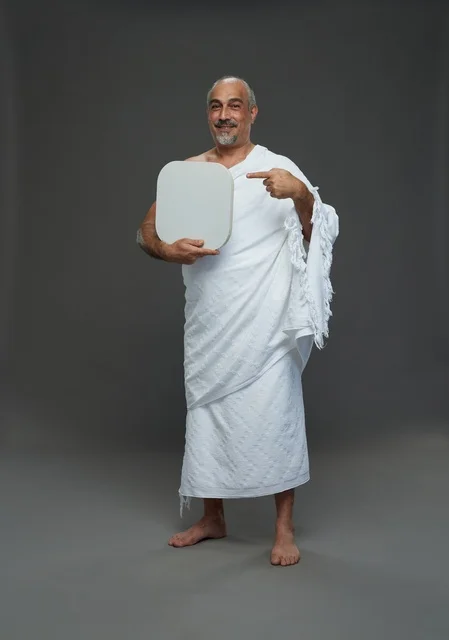 بورتريه لحاج سعودي بملابس الإحرام يحمل لوح مربع ابيض فارغ أثناء أداء المناسك, ايماءات واشارات مختلفه, كامل الجسم, خلفيه رماديه