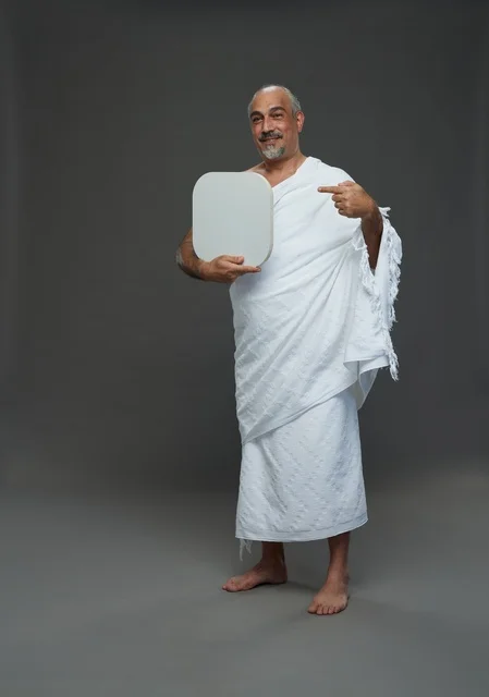 A portrait of a Saudi pilgrim in Ihram clothing holding a blank white square board while performing the rituals, with various gestures and signs, full body, gray background.