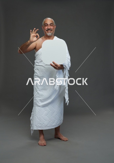 A portrait of a Saudi pilgrim in Ihram clothing holding a blank white square board while performing the rituals, with various gestures and signs, full body, gray background.