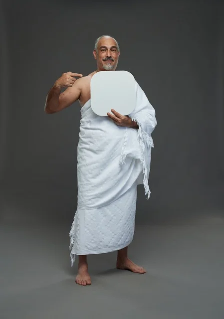A portrait of a Saudi pilgrim in Ihram clothing holding a blank white square board while performing the rituals, with various gestures and signs, full body, gray background.