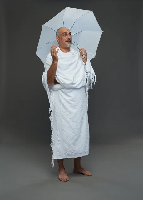 A portrait of a Saudi man in Ihram clothing holding a white umbrella while performing rituals, with various gestures and signals, full body, gray background.