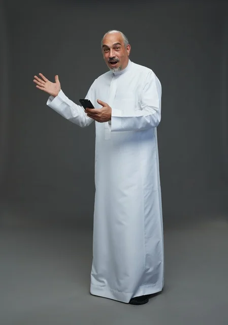 An elderly Arab Saudi Gulf man wearing a white thobe and holding a mobile phone, making various gestures and signals, full body, gray background.