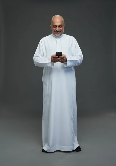رجل  عربي سعودي خليجي مسن يرتدي الزي الثوب الابيض ويمسك الهاتف المحمول,  ايماءات واشارات مختلفه , كامل الجسم, خلفيه رماديه