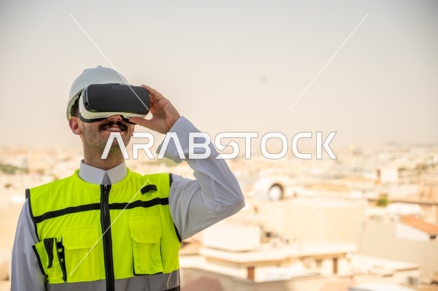  الانفتاح الحضاري في هندسة مباني المملكة العربية السعودية، مفهوم أدارة المشاريع الهندسية، صورة جانبية لمهندس عربي خليجي سعودي يرتدي الثوب التقليدي والسترة الخاصة وخوذة الحماية ينظر في نظارة واقع افتراضي ثلاثية الأبعاد، خلفية أبراج وناطحات سحاب 