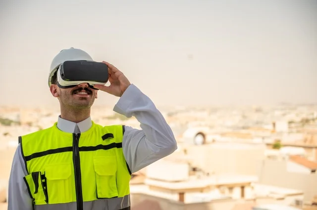 Cultural openness in the architecture of buildings in the Kingdom of Saudi Arabia, the concept of engineering project management, a side view of a Saudi Arabian Gulf engineer wearing traditional clothing, a special jacket, and a protective helmet, looking into 3D virtual reality glasses, a background of towers and skyscrapers