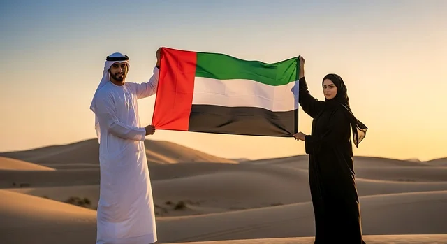 Union Day is on December 2nd, the concept of love for the homeland and belonging to it, celebrating national holidays and occasions, an Arab Gulf Emirati woman wearing a hijab and abaya holding the flag of the United Arab Emirates in her hand alongside her husband, the commemoration of Flag Day on November 3rd, and the celebration of the Emirati National Day in 1971.