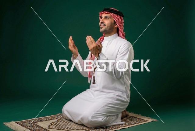 أذكار وأدعية وفرائض، الركوع والسجود والخشوع لله، رجل عربي سعودي خليجي يرتدي الثوب التقليدي والشماغ يجلس على السجادة و يؤدي فريضة الصلاة ، آداء صلاة التراويح فى شهر رمضان الكريم ، الدعاء والتضرع الى الله