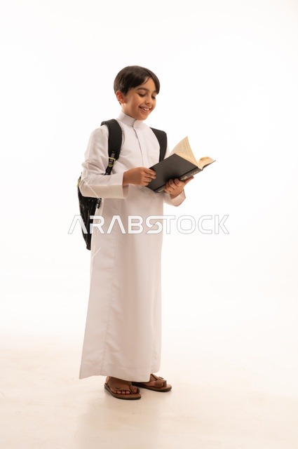 أهمية القراءة في توسيع آفاق المعرفة وزيادة المعلومات، الاجتهاد للوصول إلى النجاح، المناهج العلمية التعليمية، مفهوم العودة إلى المدارس، بورتريه لطالب عربي خليجي سعودي يرتدي الثوب التقليدي يحمل حقيبة الظهر المدرسية ويحمل بيده كتاب، صورة لكامل الجسم، خلفية بيضاء