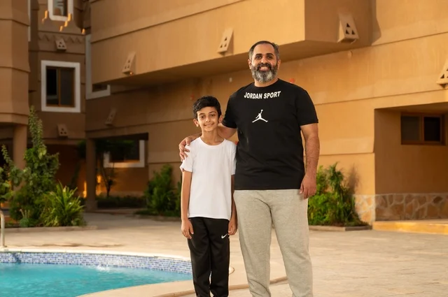 قضاء العطلة الصيفية في المنتجعات السياحية, مشاركة العائلة اللحظات الممتعة, القيام بالأنشطة الترفيهية المسلية, اب عربي خليجي سعودي يقف بجانب حوض السباحة مع ولده في إحدى الفنادق بالسعودي، ممارسة رياضة السباحة الممتعة