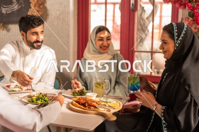 الاستمتاع بتناول الغداء في المطعم, جلسة وناسة وتعارف، بناء علاقات اجتماعية ناجحة, تبادل الأحاديث والاخبار, مشاركة الأصدقاء الأوقات الممتعة, عائلة عرب خليجيون سعوديون يجلسون على المائدة في إحدى المطاعم الراقية ويقومون بتناول الطعام بإيماءات السعادة والسرور