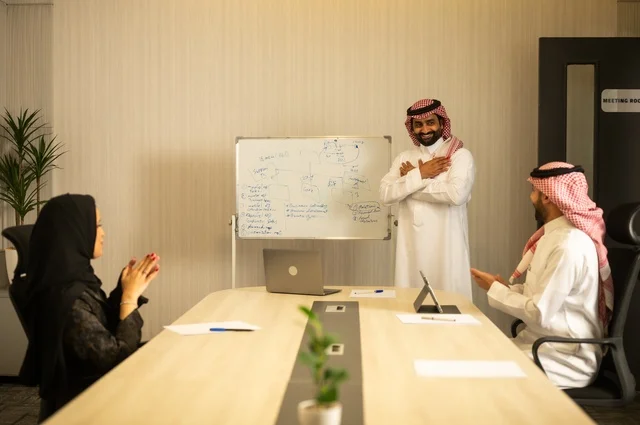استعمال السبورة لتوضيح العمليات والاجراءات المتبعة في الشركة، العمل الجماعي وروح الفريق، مناقشة خطط العمل، استخدام اللابتوب في تدوين الملاحظات، الاحترافية والتفاني في الإنجاز، فريق عربي خليجي سعودي في اجتماع داخل المكتب، ضمان فهم واضح وشامل للاعمال