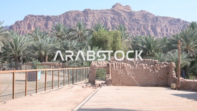 The heritage village of Al-Ula is located in the northwest of the Kingdom of Saudi Arabia, featuring an aerial view of the city of Al-Ula and the surrounding mountains. Tourism in Saudi Arabia includes historical and archaeological landmarks in the old town of Al-Ula, palm trees near the mountainous elevations, Saudi oases, and ancient mud buildings.