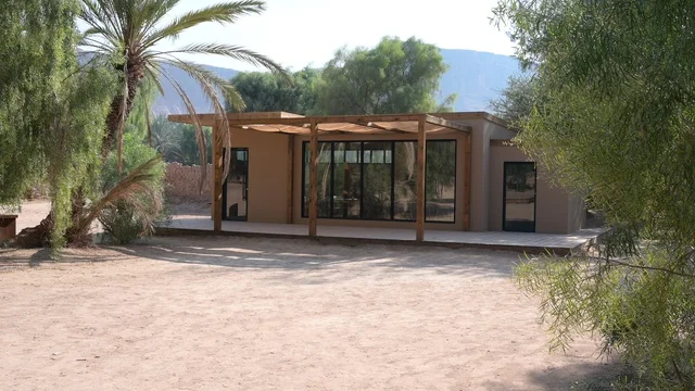 The heritage village of Al-Ula is located in the northwest of the Kingdom of Saudi Arabia, featuring an aerial view of the city of Al-Ula and the surrounding mountains. Tourism in Saudi Arabia includes historical and archaeological landmarks in the old town of Al-Ula, palm trees near the mountainous elevations, Saudi oases, and ancient mud buildings.