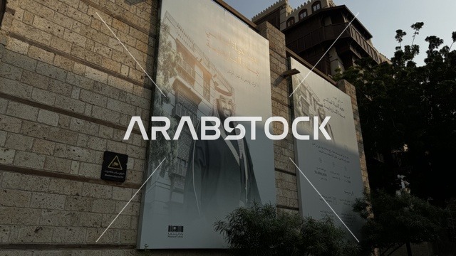 لافتة باللون الأبيض والأسود معلقة على جدار حجري، الفنون المعمارية في المدينة التاريخية في جدة، تصوير درون للحارات والتصاميم الشعبية، الأماكن السياحية في المملكة العربية السعودية، المباني الأثرية القديمة، مشاريع إعادة إحياء المنطقة